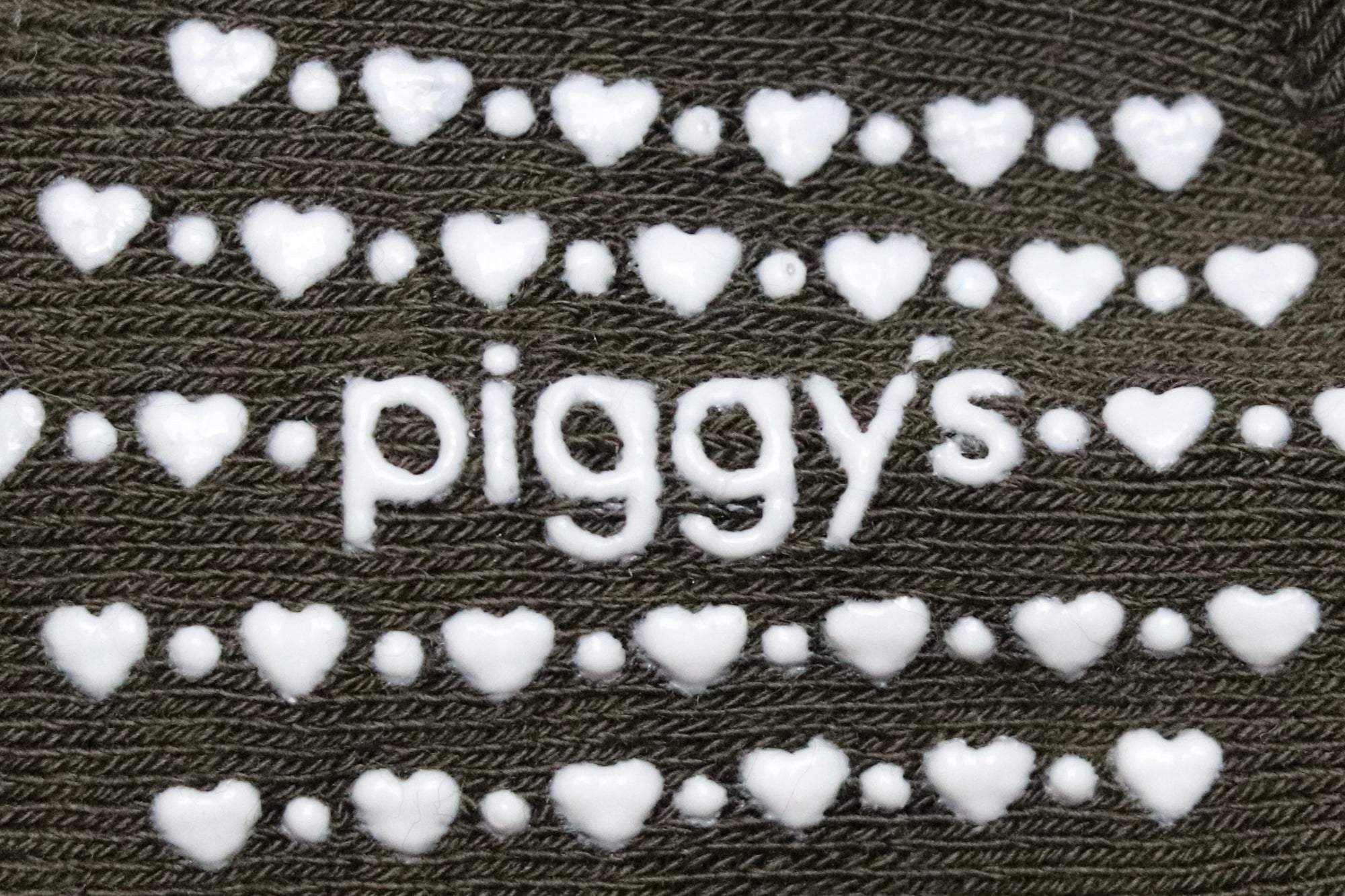 Silicone grippers of 'piggy's' surrounded by hearts and dots on Piggy's baby crew socks in the color espresso