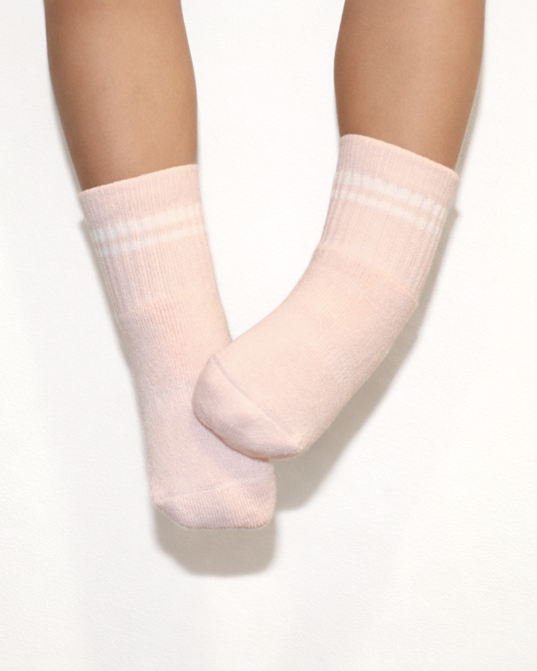 Pair of blush baby crew socks with silicone grips on an off-white background