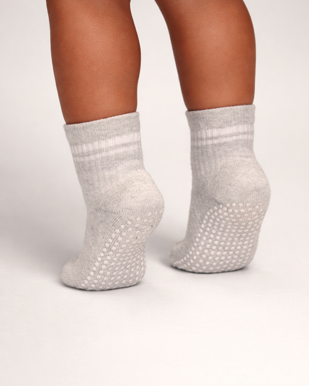 Heather grey toddler crew sock with white dot silicone grips on a grey background.