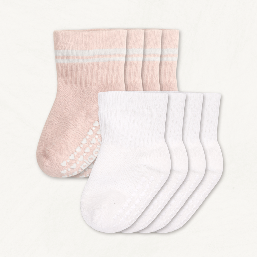 4-pack set of white and blush pink baby crew socks with white stripes and silicone grips on an off-white background