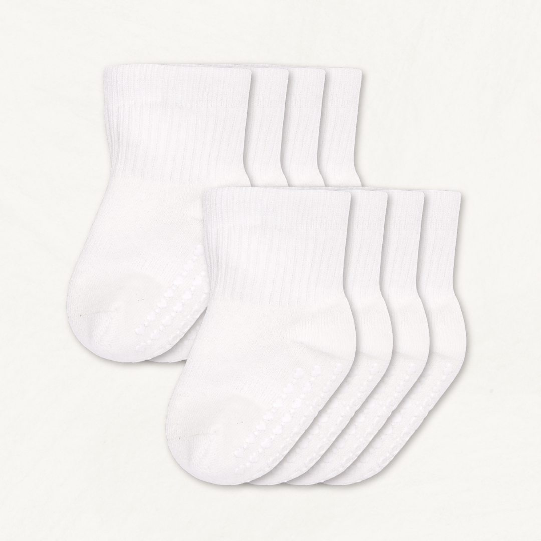 4-pack set of white baby crew socks with silicone grips on an off-white background