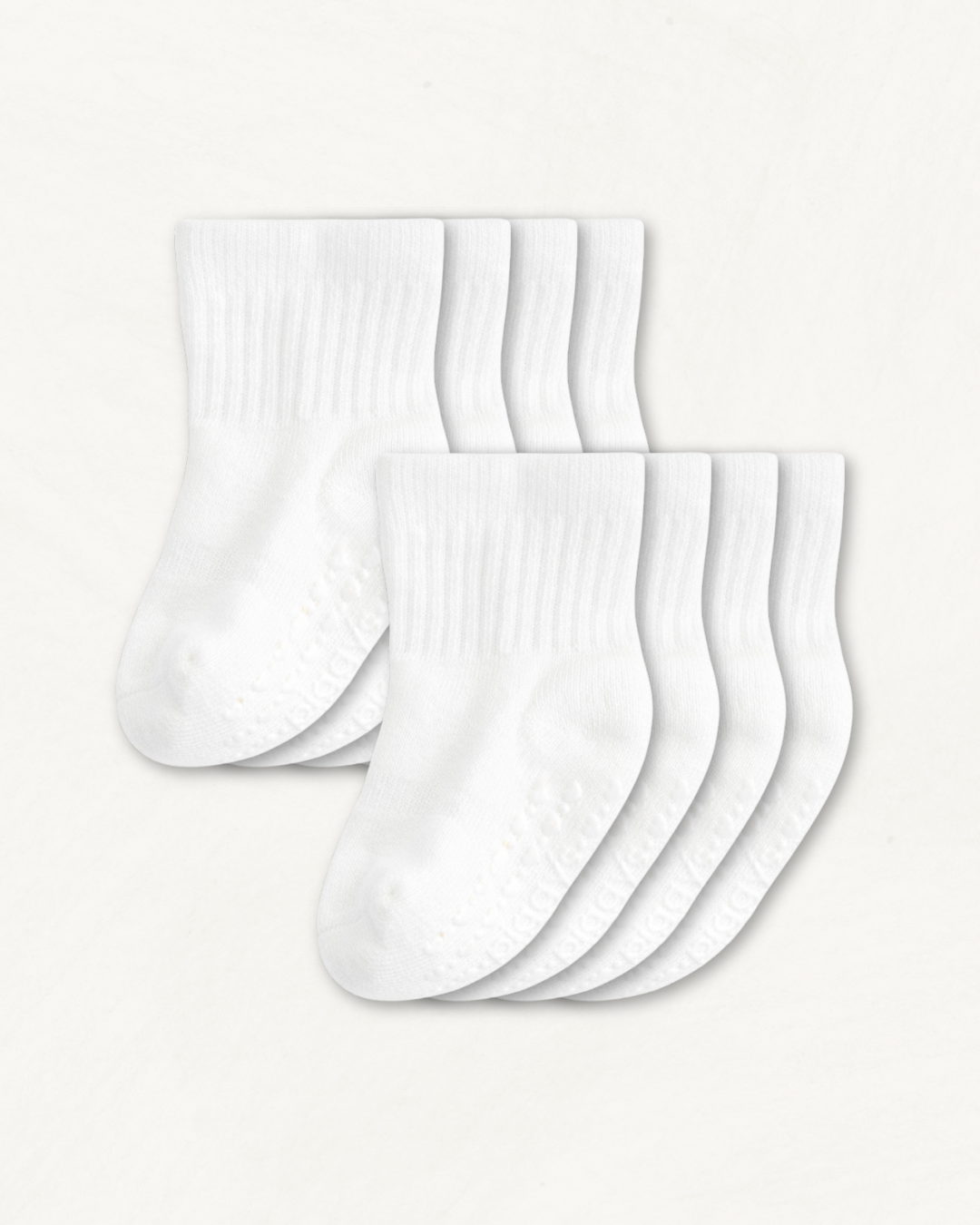 4-pack set of white baby crew socks with silicone grips on an off-white background