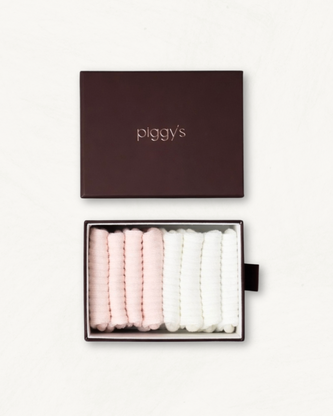 Open box displaying 2 pairs of blush and 2 pairs of white baby socks with 'piggy's' branding on a white background.