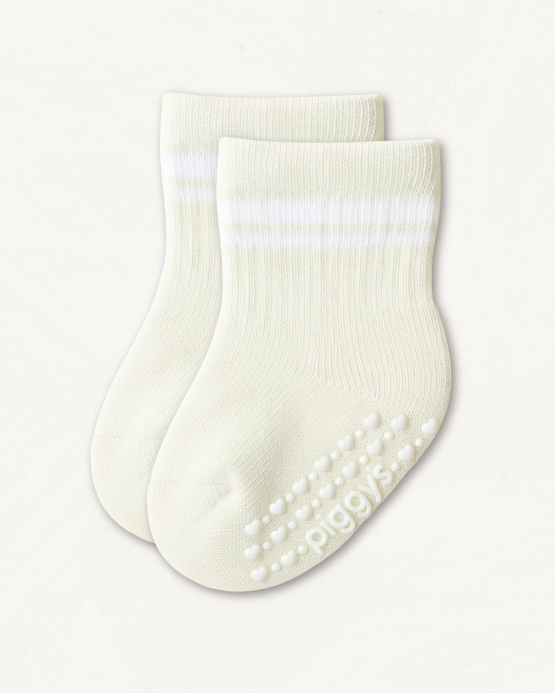 Pair of off-white crew socks with white stripes and heart pattern silicone grips on an off-white background