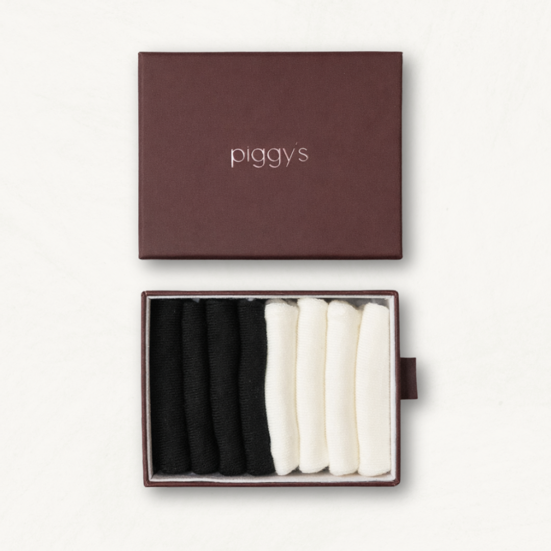 Open box displaying 2 pairs of black and 2 pairs of white toddler socks with 'piggy's' branding on a white background.