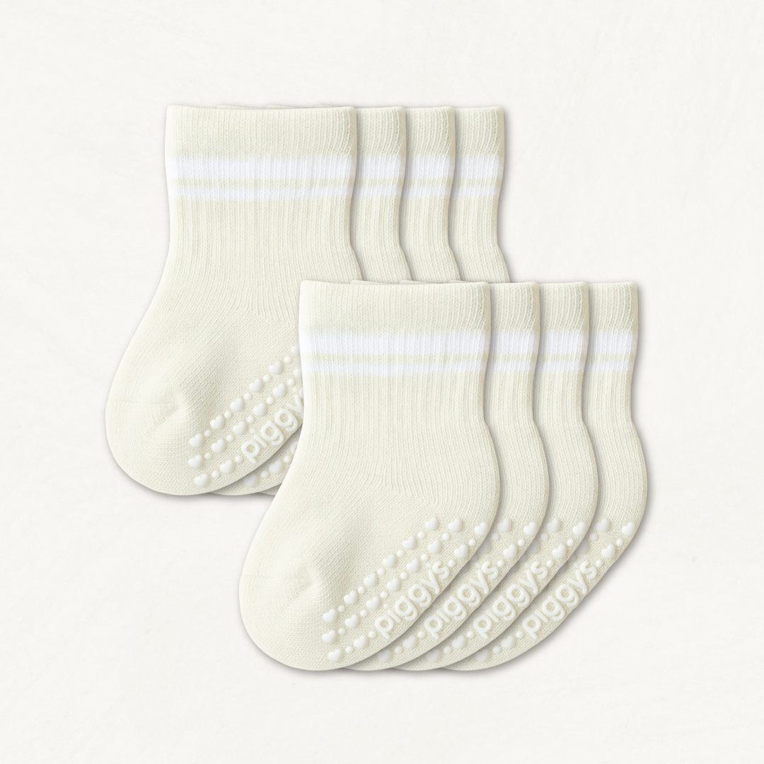 Set of off-white baby crew socks with white stripes and silicone grips on an off-white background
