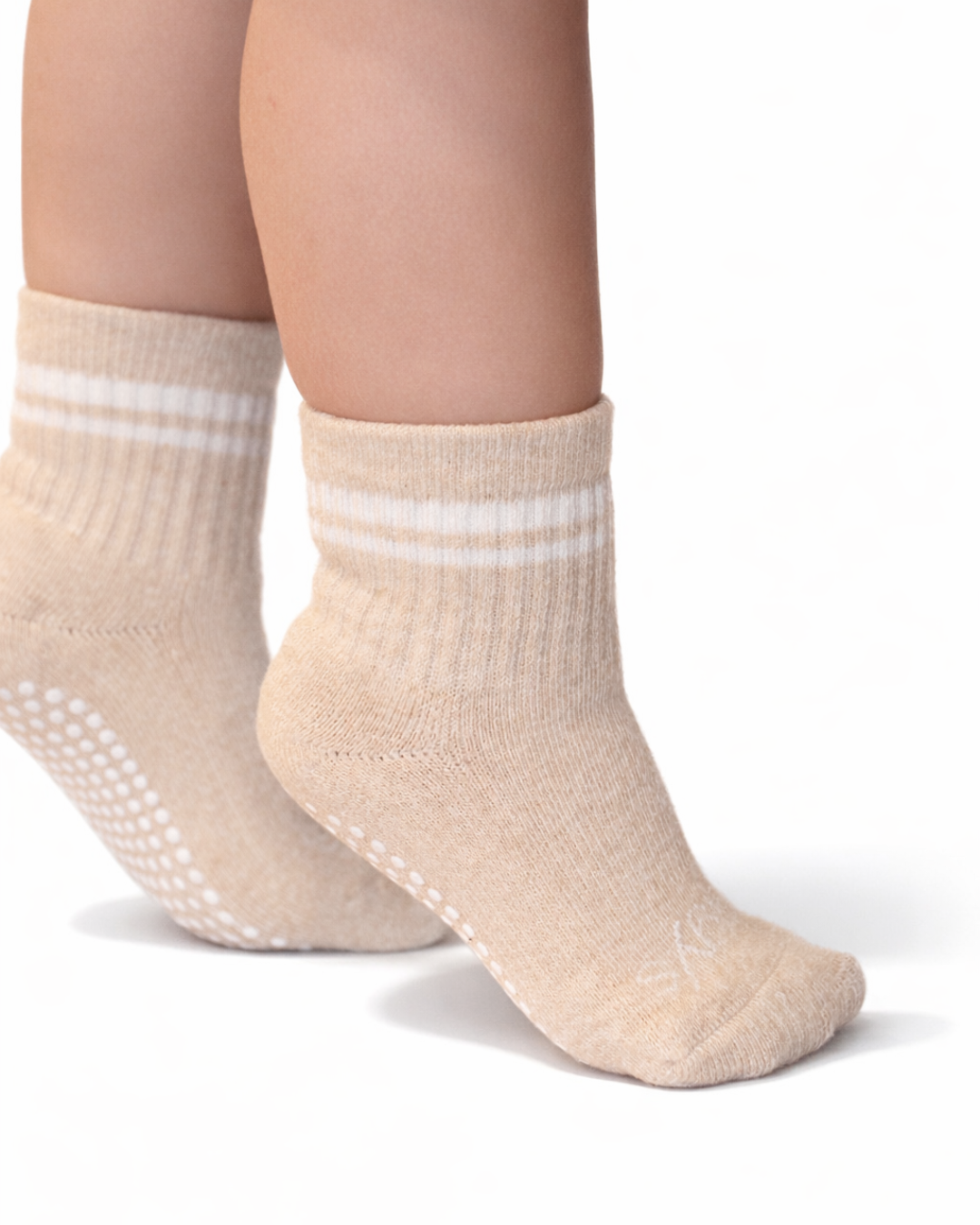 Pair of heathered beige toddler crew socks with silicone grips on an off-white background