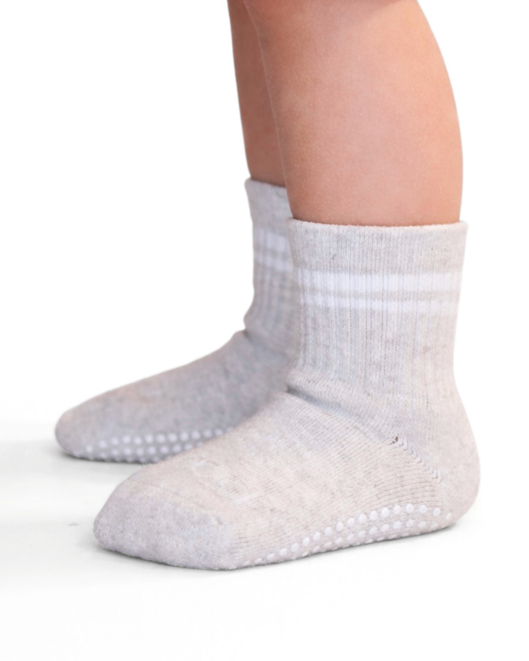 Pair of heathered light gray toddler crew socks with silicone grips on an off-white background