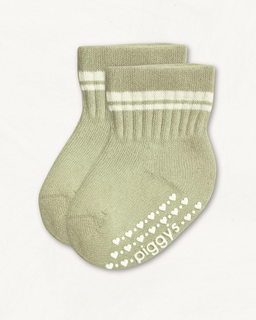 Pair of light sage crew socks with white stripes and heart pattern silicone grips on an off-white background